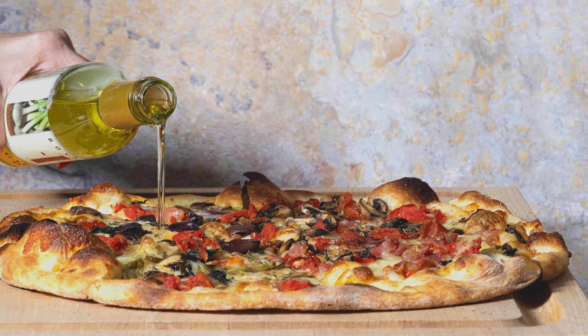 Garlic oil being drizzled over a pizza