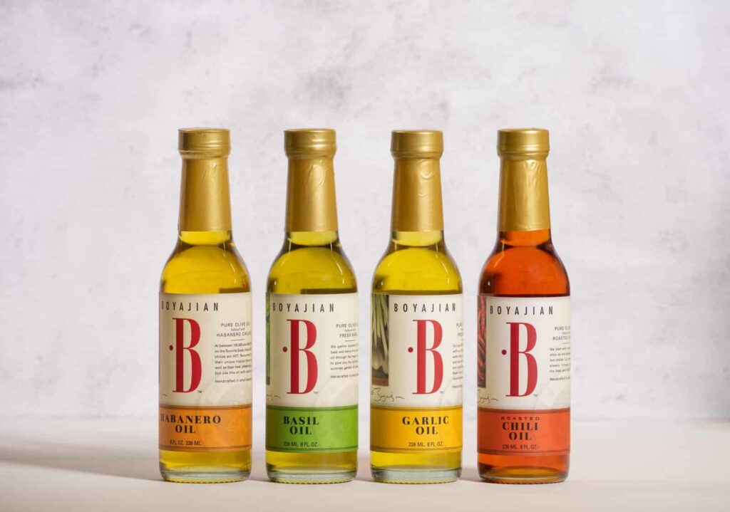 Four bottles of Boyajian infused oils: Habanero, Basil, Garlic, and Roasted Chili, lined up on a gray background.